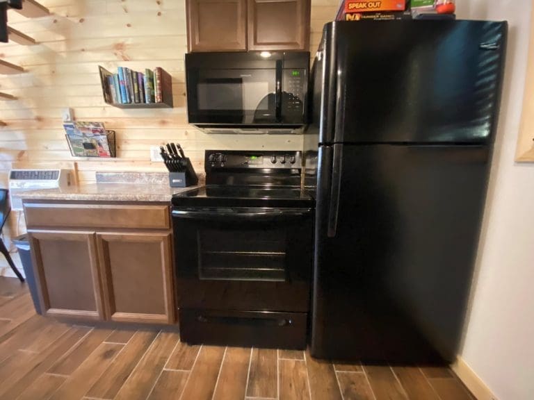 Oven, refrigerator, microwave, countertop and cabinets, and ac unit in a 400 sq Ft deluxe cabin kitchen