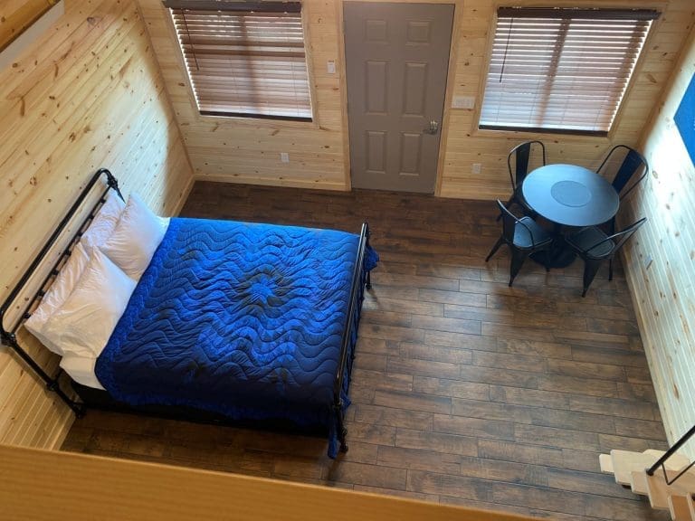 View from the loft overlooking bed and table with seating